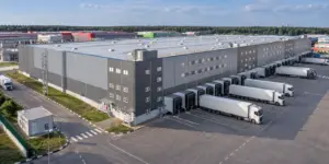 Архитектурный вид большого склада: кровля, протяжённый ряд погрузочных доков и грузовая площадка